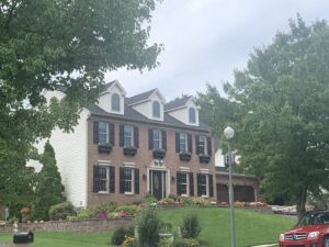 Angled distance view of beautiful brick colonial house with dormers added to roof.