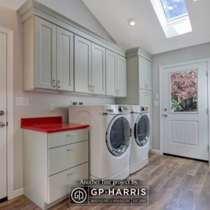 Large laundry room with white cabinets, red countertop, and a skylight.