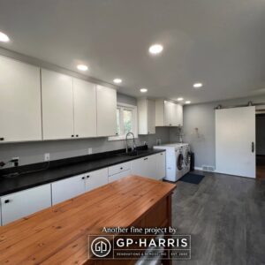 Huge custom laundry room with extensive white cabinets, black countertops, and a wood folding island.